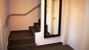 Eine Treppe mit Handlauf, eine Tür mit Spiegel und ein Lichtschalter an der Wand.