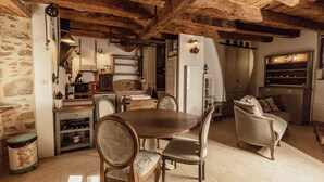 A rustic kitchen with wooden beams, a dining table, and a sofa. - Les 3 Clefs de GaYa Well-being & private spa: swim spa, sauna, massage bed. (Saint-Jean-Ligoure)