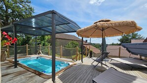 A wooden deck with a hot tub, a covered seating area, and a view of the surrounding landscape. - Les 3 Clefs de GaYa Well-being & private spa: swim spa, sauna, massage bed. (Saint-Jean-Ligoure)