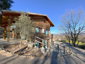 A rustic wooden cabin with a porch and a staircase leading to the entrance.