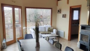 A spacious dining area with a long table and chairs, a sofa, and a kitchen area with a stove. - L'Escapade Ardéchoise (Fons)