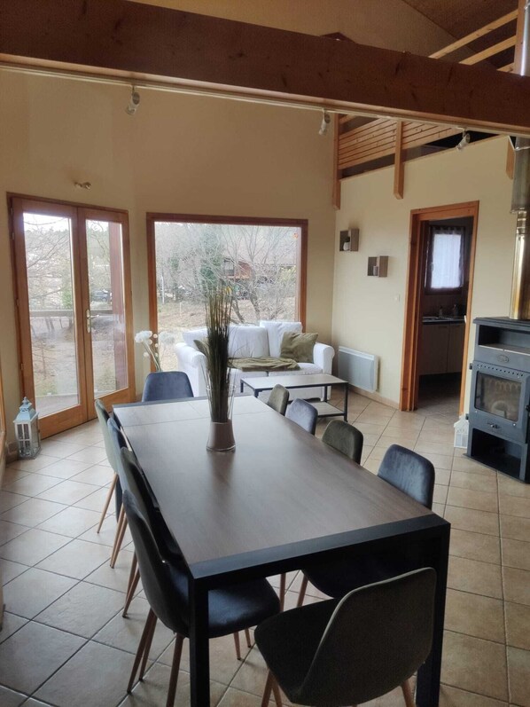 A spacious dining area with a long table and chairs, a sofa, and a kitchen area with a stove.