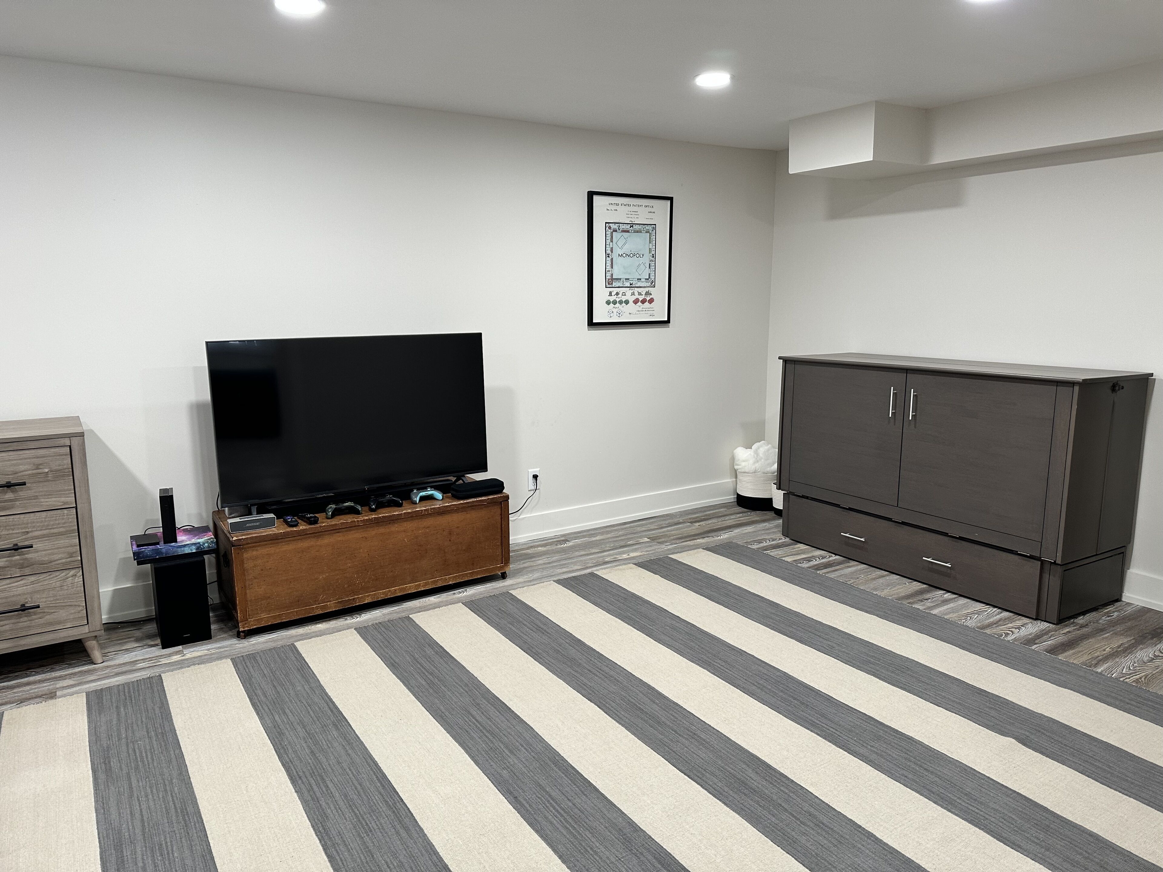 A living room with a flat-screen TV, a cabinet, and a striped rug.