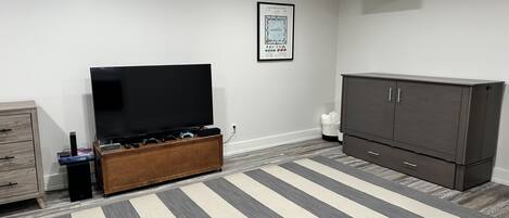 A living room with a flat-screen TV, a cabinet, and a striped rug.