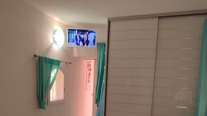 A bedroom with a bed, a nightstand, a lamp, a sliding door, and a television on the wall. - Peace and relaxation in green Provence (Entrecasteaux)
