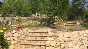 A stone staircase leading up to a stone wall with potted plants and trees in the background. - Peace and relaxation in green Provence (Entrecasteaux)