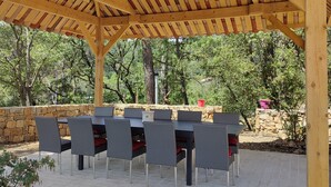 An outdoor patio with a wooden pergola, stone walls, and a table with chairs. - Peace and relaxation in green Provence (Entrecasteaux)