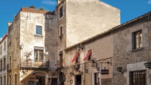 A narrow street with buildings featuring balconies, outdoor seating, and a restaurant sign. - CAN FELIP Apartment with Fantastic Views (Palafrugell)