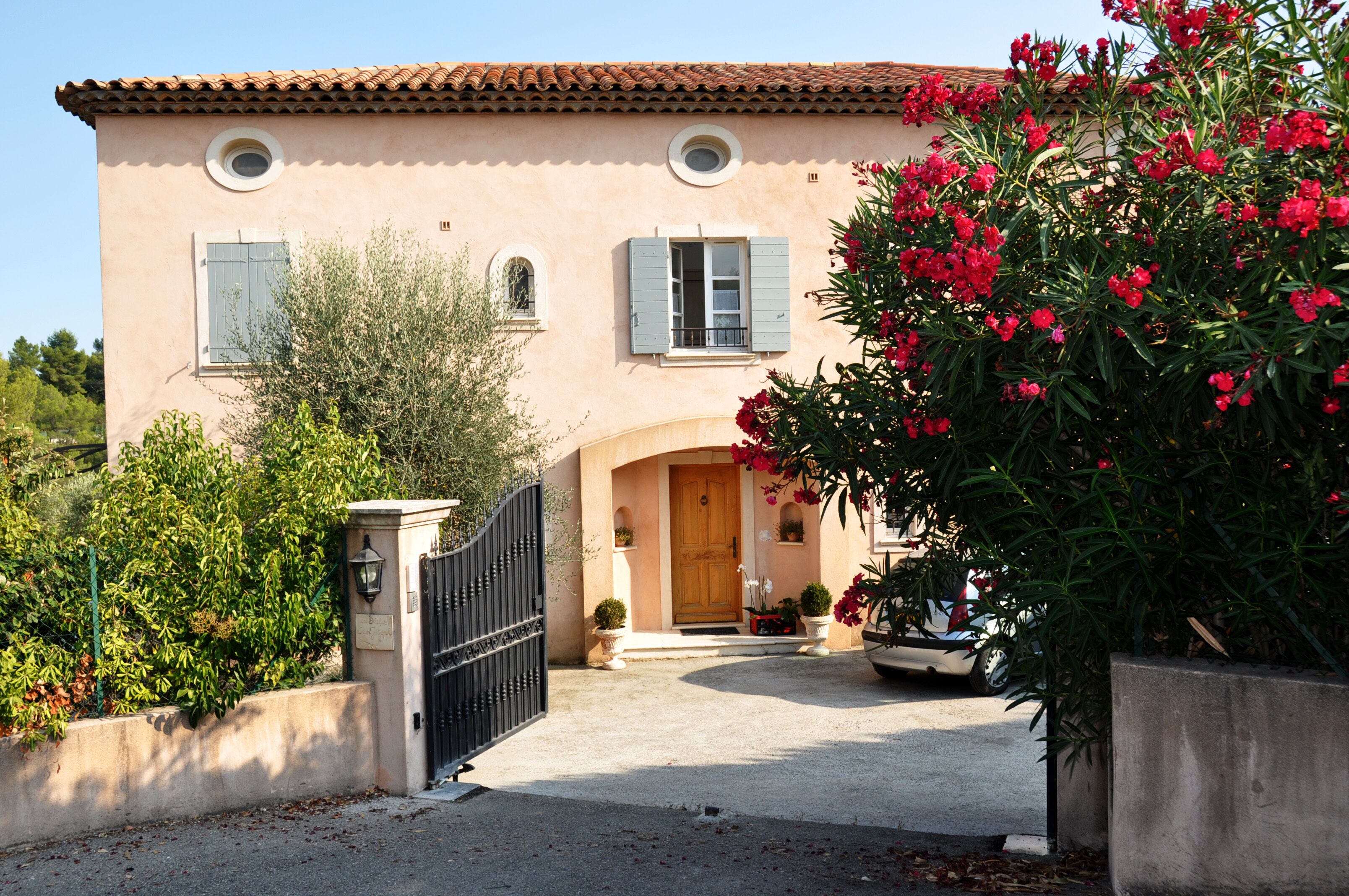 A two-story building with a tiled roof, a gated entrance, and potted plants.