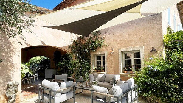 An outdoor patio with a sofa set, a table, and a large canopy. - Large air-conditioned family villa with private pool in Provence, French Riviera (Le Rouret)