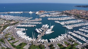 An aerial view of a marina with numerous boats docked in a circular pattern, surrounded by a cityscape. - First-Row Sea View Retreat · Old Town Antibes · 2BR with Balcony (Antibes)