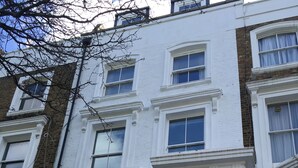 A white townhouse with a green door, multiple windows, and a staircase leading to the entrance. - A Newly Refurbished Apartment in Notting Hill, London (London)