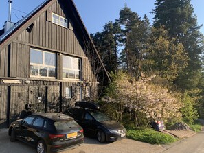A two-story wooden building with a sloped roof, large windows, and a car parked in front. - Apartment Eulennest in an idyllic forester's lodge, individual and modern (Forbach)