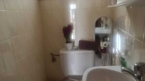 Un bagno piccolo con il water, un lavandino e una finestra sopra il water.