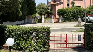 A pink building with a stone-paved entrance, surrounded by greenery and trees. - RED 1 Apartment (Portiglioni)