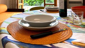 A dining table set with plates, a bottle of wine, and a glass, with a view of greenery and a building outside. - RED 1 Apartment (Portiglioni)