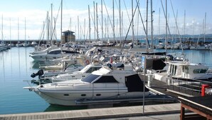 A marina with multiple boats docked, a small building in the background, and a clear sky. - RED 1 Apartment (Portiglioni)