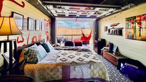 A cozy room with a bed, a chair, a desk, and a hammock. - 3 River Cabins - Private Group Retreat - Downtown Sparta! (North)