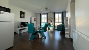 Ein modernes Wohnzimmer mit Essbereich, einer Küche und einem großen Fenster, das für natürliches Licht sorgt.