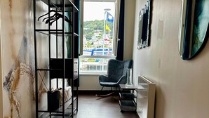 Ein Flur mit Marmorwand, einer schwarzen Metallregal-Anlage, einem Stuhl und einem Fenster mit Blick auf Flaggen und Gebäude.