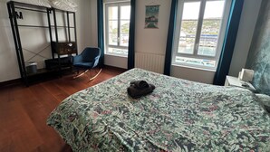 A bedroom with a bed, a rocking chair, a wardrobe, and a window with a view.