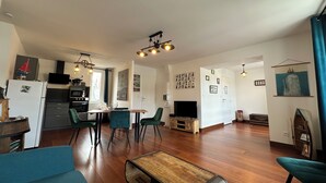 A modern living room with a wooden coffee table, teal sofas, and a dining area with a wooden table and chairs.