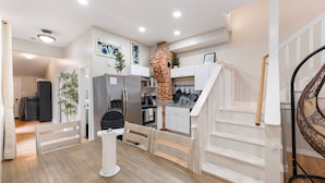 A compact kitchen with white cabinets, a brick oven, and a dining area with a white table and chairs. - 4 Queen Beds | High Speed Wifi (Fort Worth)
