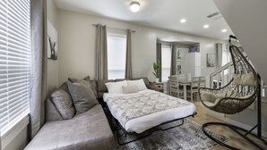 A bedroom with a bed, a sofa, a hanging chair, and a dining area. - 4 Queen Beds | High Speed Wifi (Fort Worth)