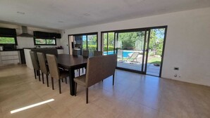 A spacious dining area with a large table and chairs, a kitchen area with modern appliances, and a sliding glass door leading to a pool area. - La Tribu, House with pool and whirlpool, ideal for families (Sierra de los Padres)
