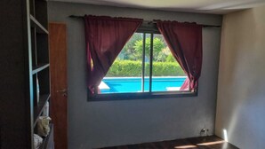 A room with a window overlooking a swimming pool, a wooden door, and a small shelf with items on it. - La Tribu, House with pool and whirlpool, ideal for families (Sierra de los Padres)