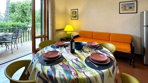 A dining area with a table set for four, a sofa, a lamp, and a painting on the wall.