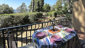 An outdoor patio with a table set for dining, surrounded by metal chairs and a railing.