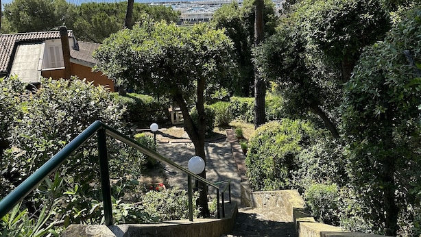 A stone staircase leading up to a terrace with a view of the sea and boats.