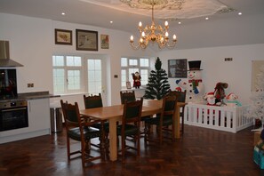 A spacious dining area with a wooden table and chairs, a chandelier, and a Christmas tree. - Indoor heated pool, games room and tennis court all private. (Caergwrle, North Wales)