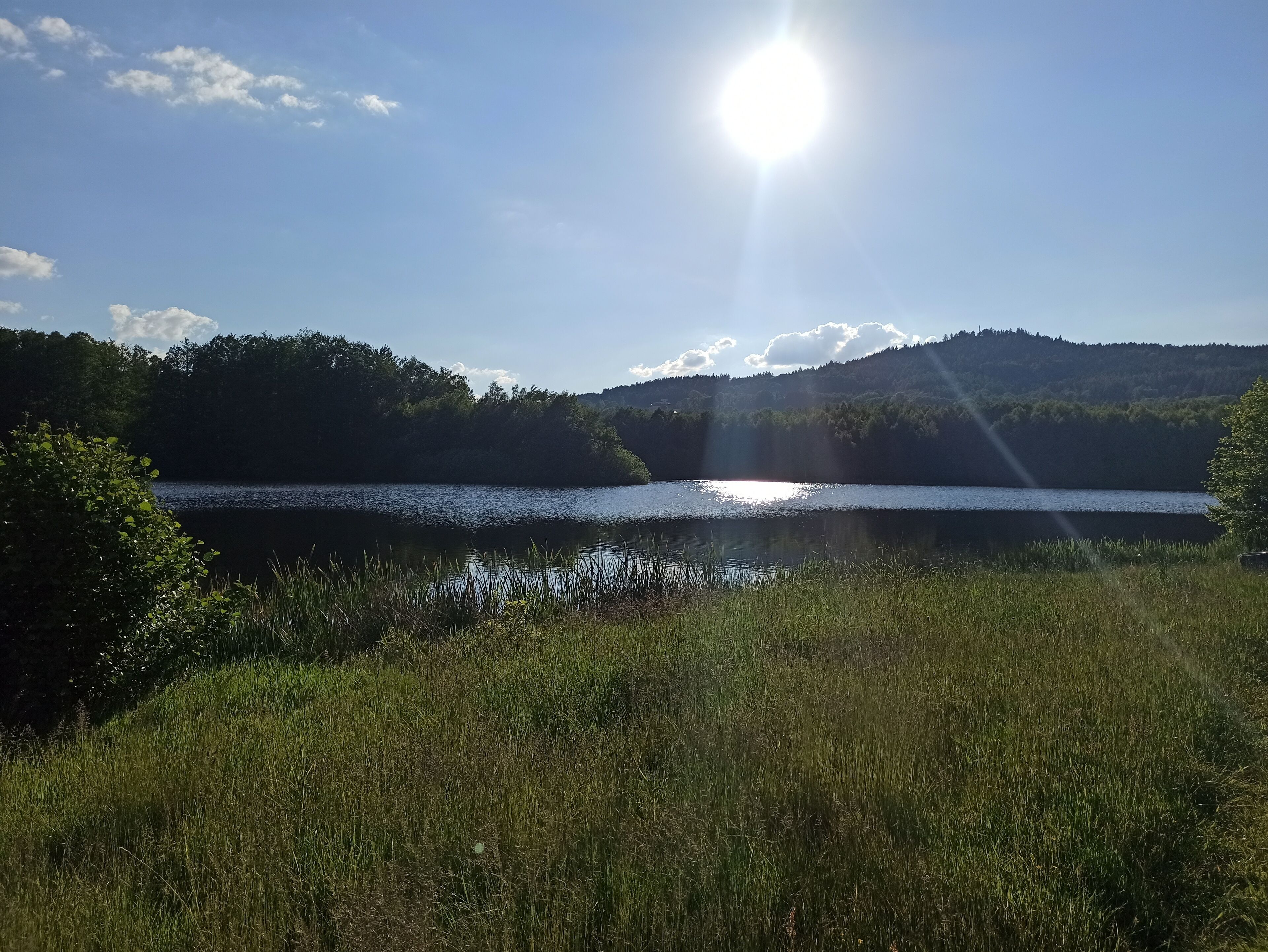 Ein See mit klarem Himmel und Sonnenschein, der sich im Wasser spiegelt.