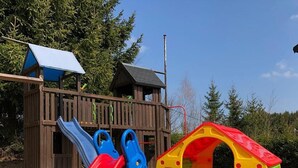 A playground with a slide, climbing steps, and a playhouse. - 5-star apartment, 60 sqm, 2nd floor, family-friendly, WiFi, playground in the garden  (Bad Brambach)