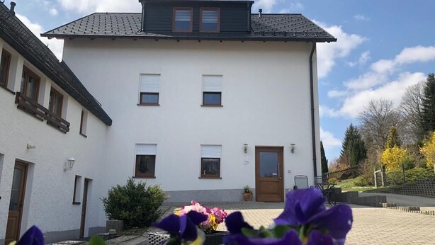A white building with a dark roof, multiple windows, and a door. - 5-star apartment, 60 sqm, 2nd floor, family-friendly, WiFi, playground in the garden  (Bad Brambach)