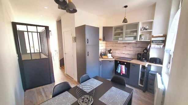 Una cucina compatta con elettrodomestici moderni, una zona pranzo con tavolo e sedie, e un angolo cottura.