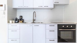 A modern kitchen with white cabinets, a stainless steel sink, and a black oven. - Fantastic 1BR Apartment with Parking in the city center (Jerusalem)