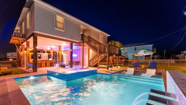 Un espace piscine comprenant un jacuzzi, des chaises longues et une terrasse couverte.