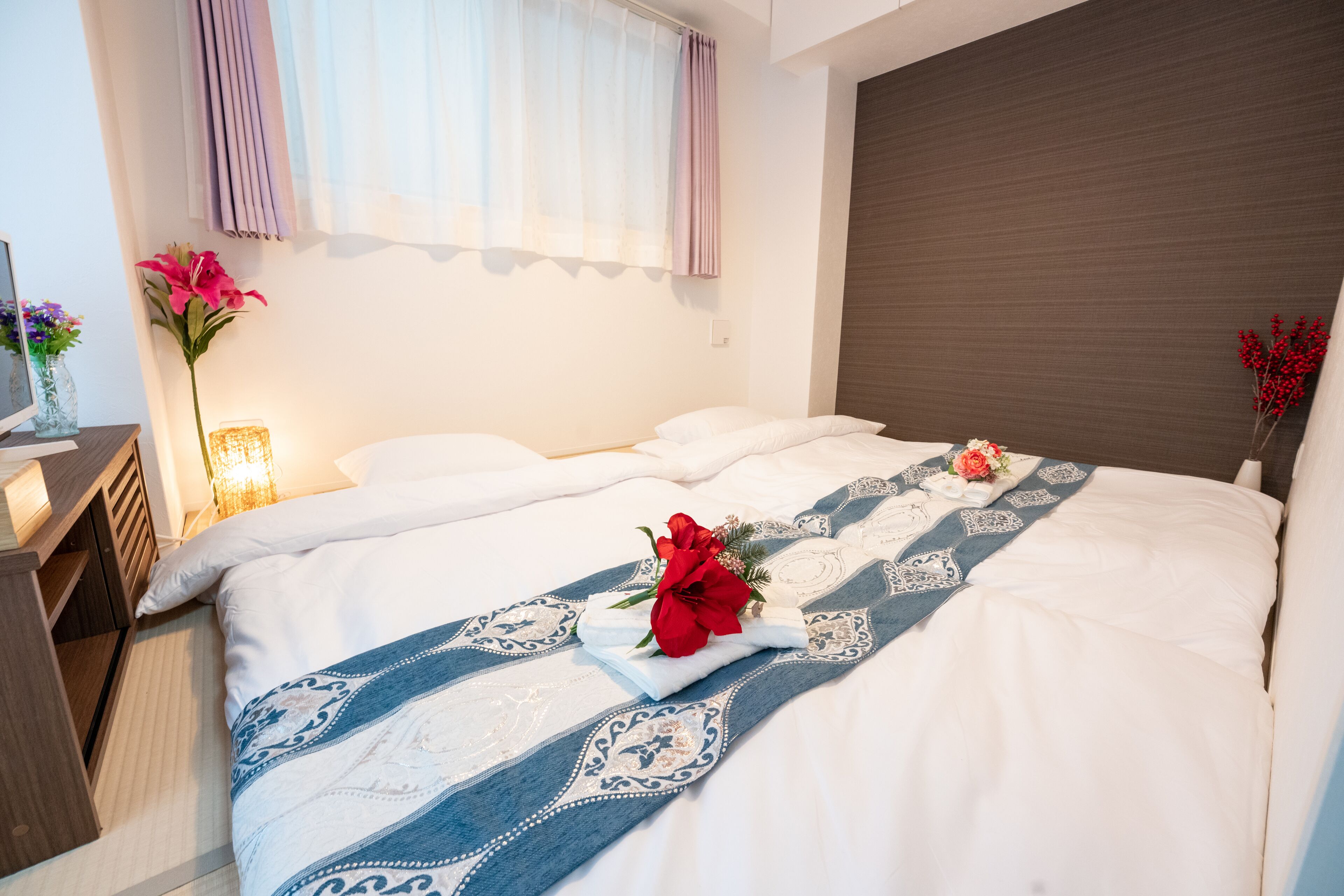 A hotel room with a large bed, a nightstand, a lamp, and a window with curtains.