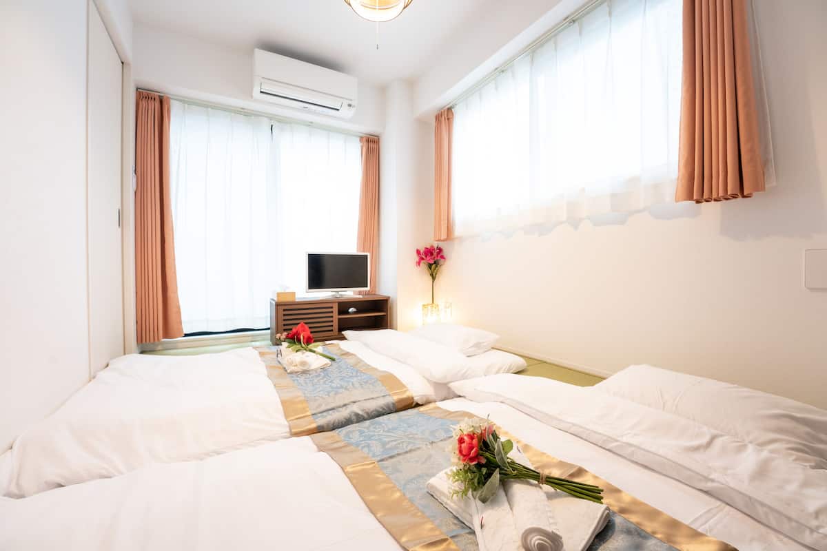 Quarto de hotel com duas camas, televisão e mesa com abajur.