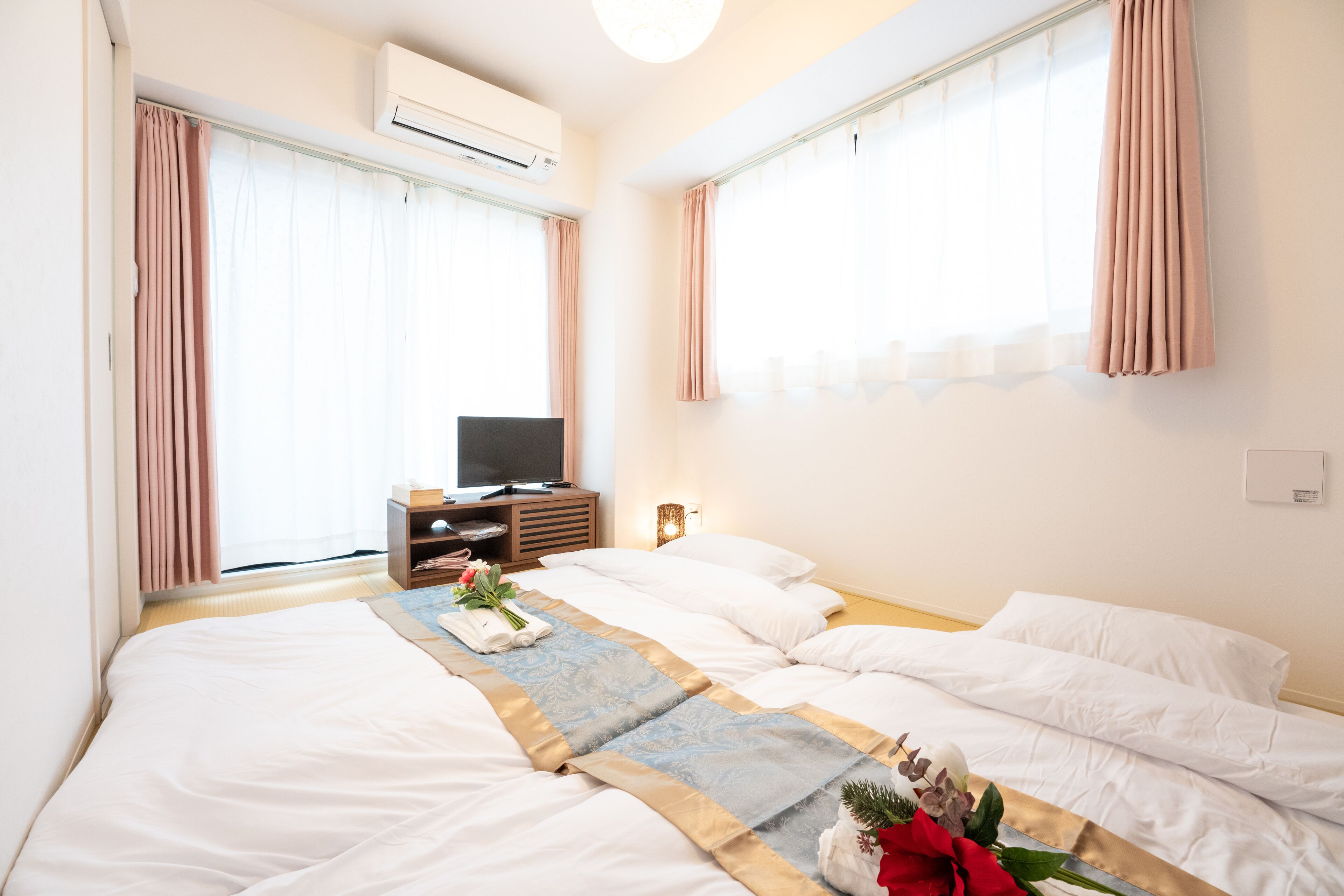 Ein Hotelzimmer mit zwei Betten, einem Fernseher und einem Fenster mit Vorhängen.