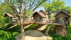 Una estructura tipo casa en árbol con una terraza de madera y una plataforma de hormigón.