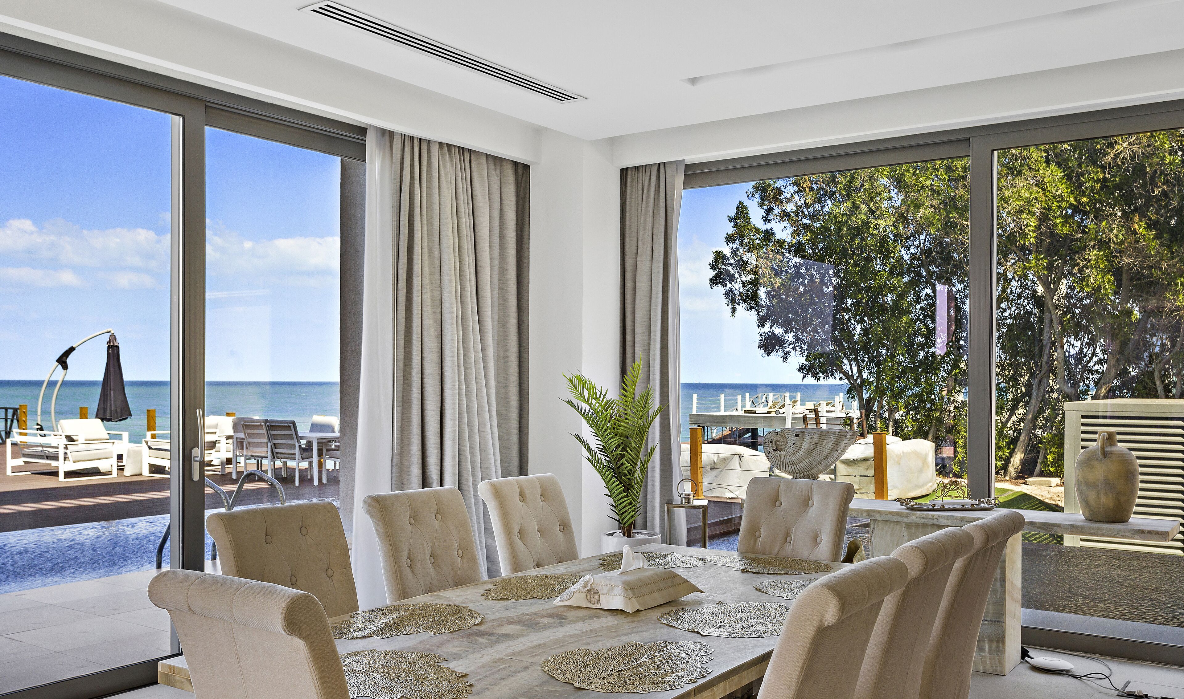 Ein Essbereich mit einem Tisch für sechs Personen, großen Fenstern mit Meerblick und einem Balkon mit Sitzgelegenheit.