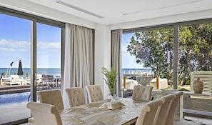 A dining area with a table set for six, large windows with ocean views, and a balcony with outdoor seating. - WelHome - Extraordinary Giant Water Villa on Nurai Island (Abu Dhabi)