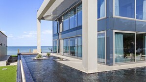 Ein modernes Gebäude mit großen Glasfenstern, einem Pool und Meerblick.