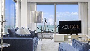 Ein modernes Wohnzimmer mit großem Fernseher, bequemen Sitzmöglichkeiten und Meerblick.