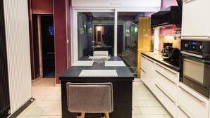 A modern kitchen with a dining area, featuring a black countertop, white cabinets, and a large window. - TOWNHOUSE WITH GARDEN NEAR STATION (Dunkerque)