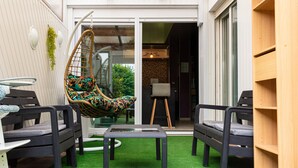 A patio with artificial grass, a hanging chair, and a table. - TOWNHOUSE WITH GARDEN NEAR STATION (Dunkerque)